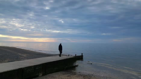 hombre caminando hacia el final del muelle al atardecer en la playa de fleetwood, lancashire, reino unido