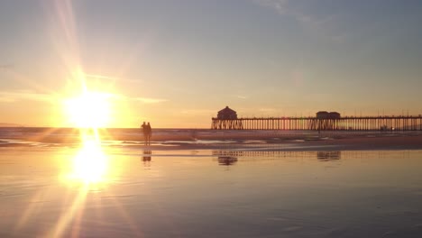 un lapso de tiempo de 4k al atardecer de una familia divirtiéndose en la marea baja de la playa con el muelle en el fondo