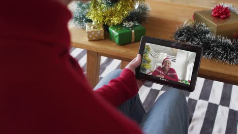 Caucasian-man-waving-and-using-tablet-for-christmas-video-call-with-smiling-woman-on-screen