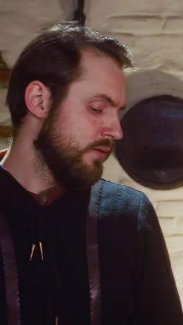 los amigos compran bebidas en la taberna medieval. el pobre invitado pone la moneda en el mostrador y se lleva las tazas en la antigua posada. los clientes nerviosos visitan el pub por alcohol