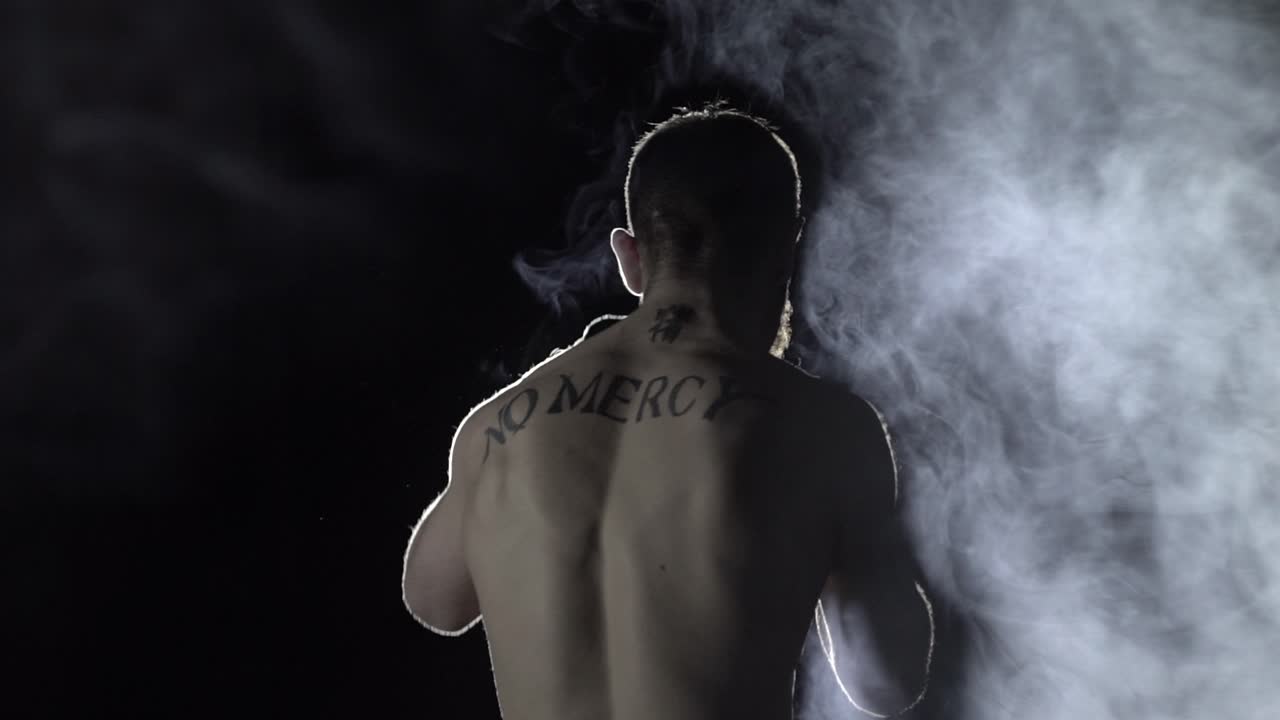 el boxeador hace calentamiento en el fondo de los reflectores y el humo