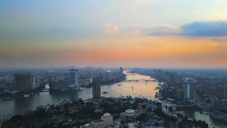 Aerial-of-the-Nile-River-meanders-through-Cairo-city,-with-a-drone-gliding-past-the-Cairo-Tower-in-Cairo,-Egypt,-embodying-the-concept-of-urban-vitality-and-architectural-marvels