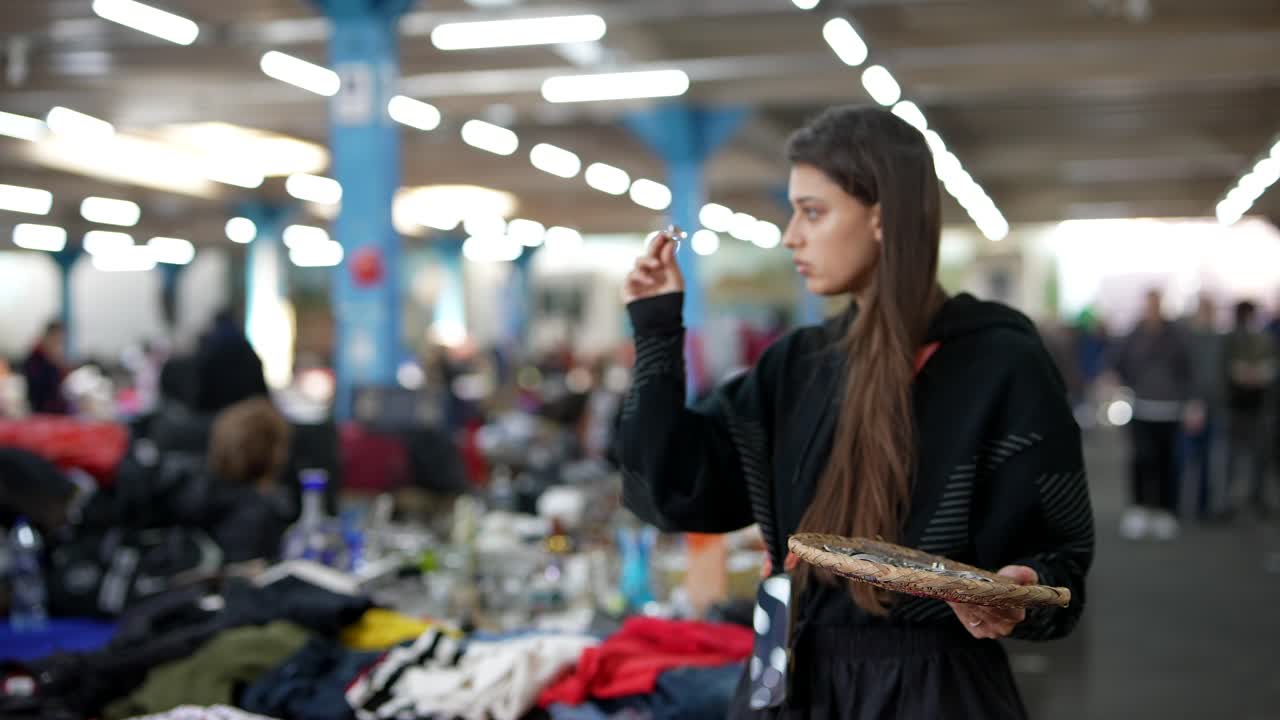 mujer examinando un artículo pequeño en un mercado de pulgas