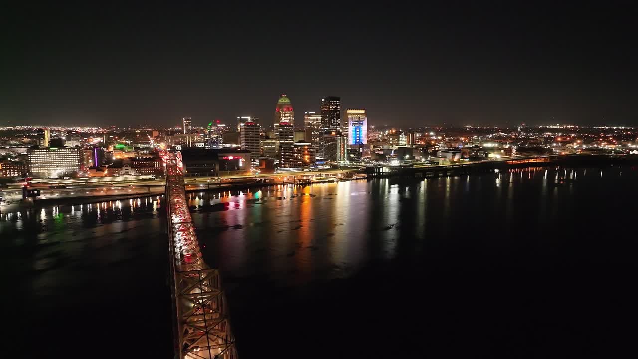 Louisville, Kentucky skyline at night with bridge in foreground with drone video moving in up high