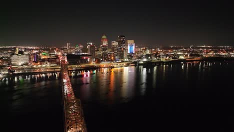 louisville, kentucky skyline at night with bridge in foreground with drone video moving in up high