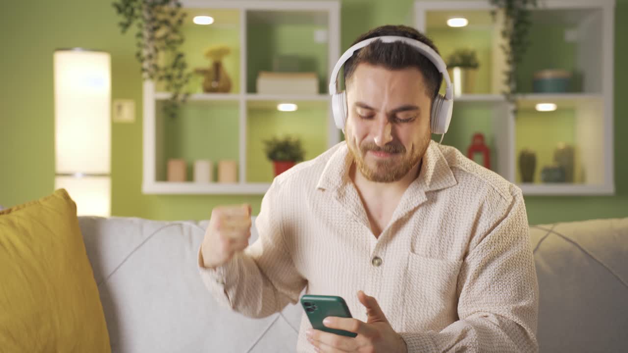 hombre escuchando música divertido mira el teléfono y baila.