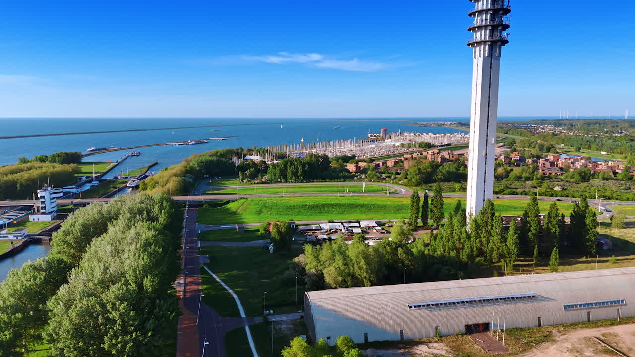 Flight over the green waterfront of Lelystad, the Netherlands. View on the vast waterscape of lake Markermeer with a large yacht club at the shore.