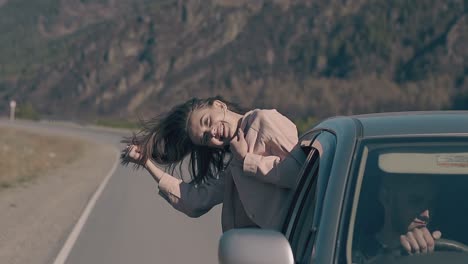 una chica bonita se inclina hacia fuera de un coche antiguo sonríe y ama la vida