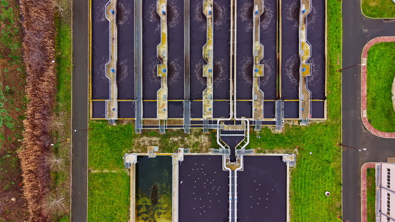 Water treatment facility view from above showing multiple tanks and green spaces during daytime