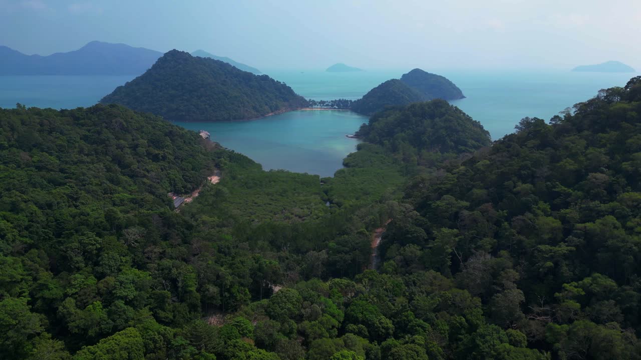 lush double mountain island with beach surrounded by turquoise sea and blue skies. Breathtaking aerial view flight ascending drone