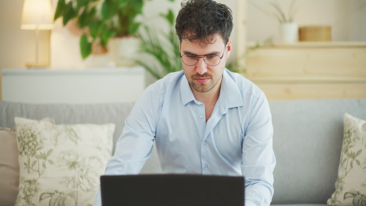 hombre sonriente escribiendo en una computadora portátil en casa