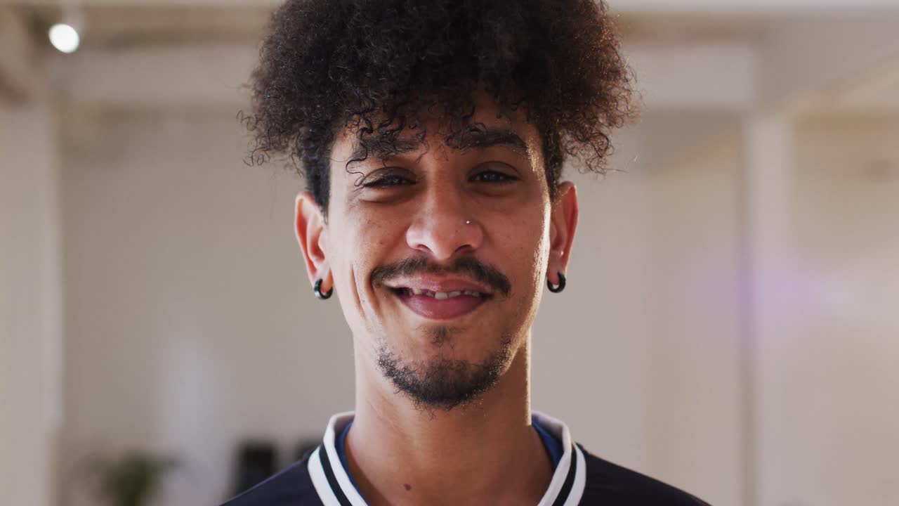 retrato de un feliz hombre biracial mirando a la cámara en un estudio de baile, cámara lenta