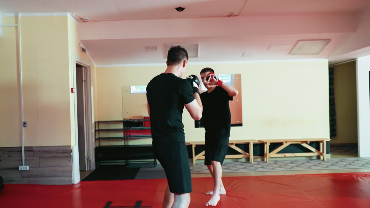 Fighters facing off inside martial arts gym, standing in fighting stances with gloves raised, preparing for sparring match, showing discipline, focus, determination, concentration during training