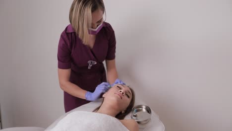 A Woman is Receiving a Rejuvenating Facial Treatment in a Beauty Salon. A woman is currently receiving a facial treatment at a beauty salon, where she is focusing on her personal care and skincare routine