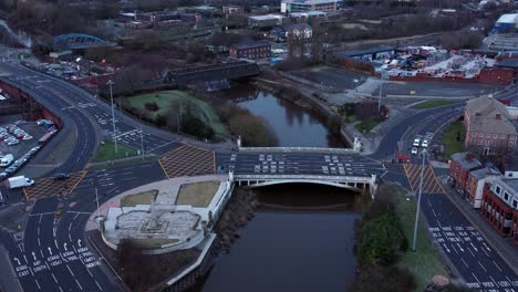 aerial early morning city street traffic commuting intersection lanes crossing curved river slow lowering shot