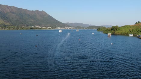 hong kong bay with small boats and surrounding green landscape, low pass aerial view