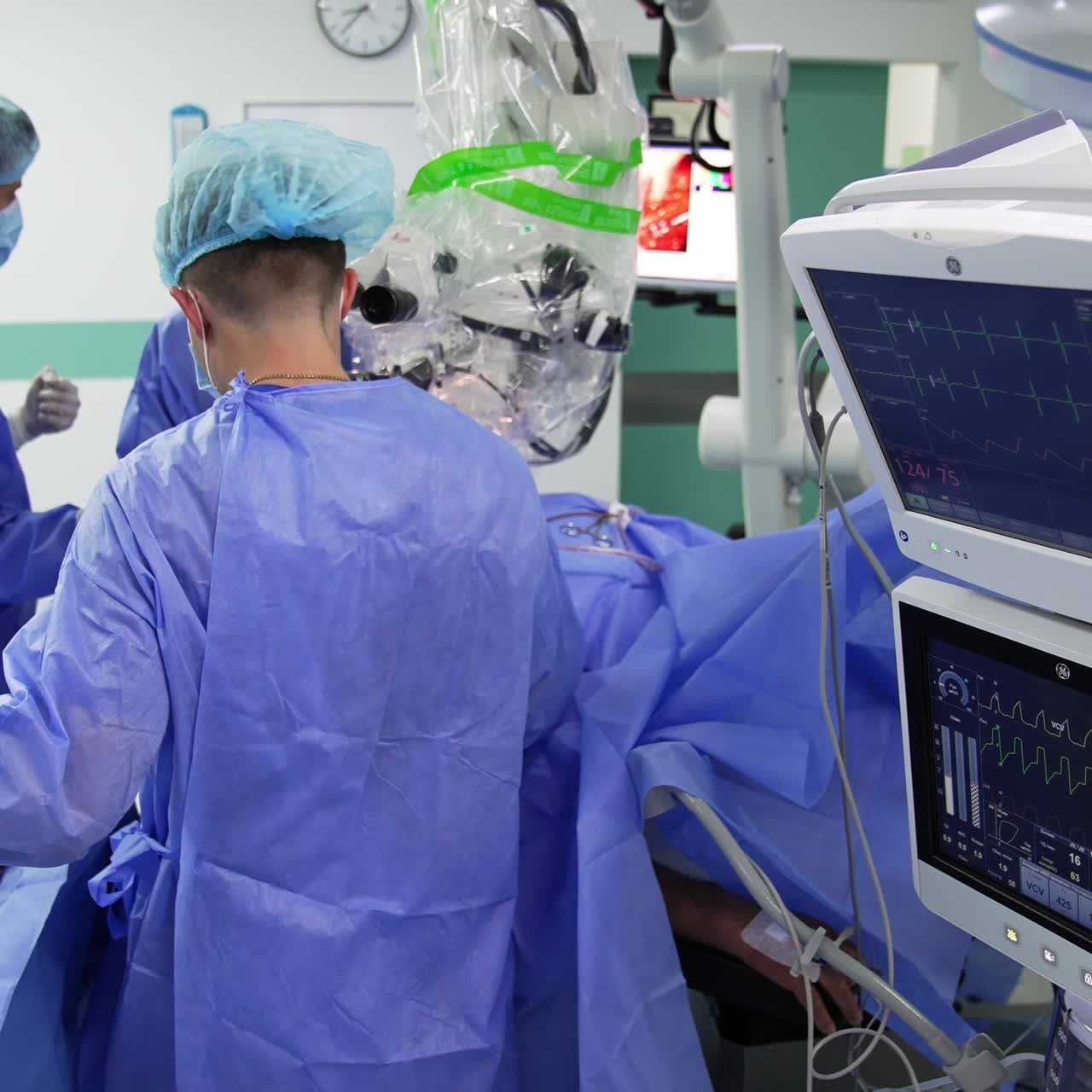 Present-day operational theatre with procedure going on. Doctors conducting surgery using metal tools. Screens on at foreground