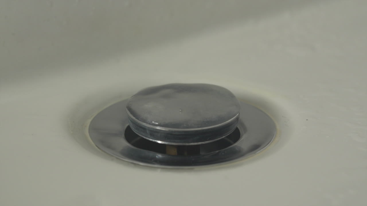 Water droplets falling quickly into the basin of the sink