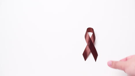 detail of male hand holding ribbon in brown color over white background