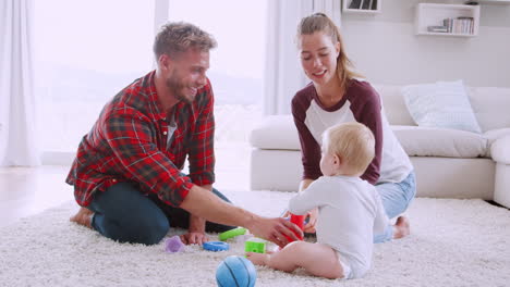 young couple playing with their toddler on the floor at home