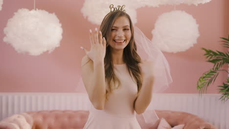 close up view of a happy bachelor girl with headdress and veil showing her engagement ring to the camera