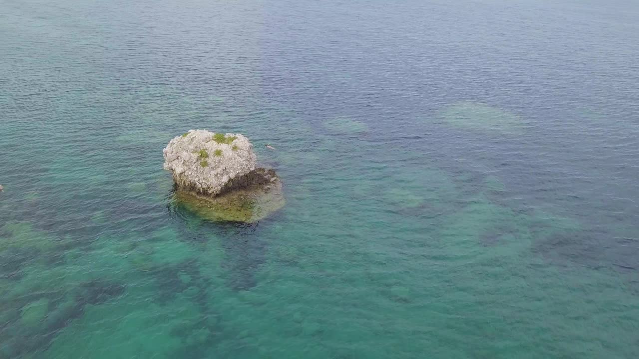 imágenes de drones giratorios hacia adentro de formación rocosa rodeada de mares poco profundos frente a la costa de grecia cefalonia