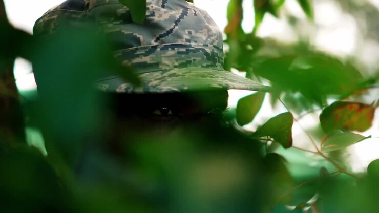 Military man standing behind the leaves