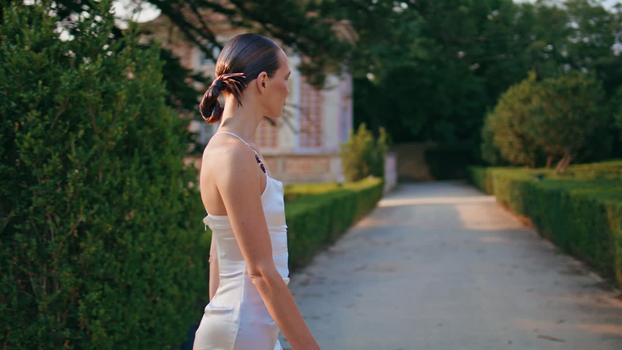 우아한 소녀가 산책하는 풍경 여름날. 미소 짓는 여자가 녹색 정원을 산책하고