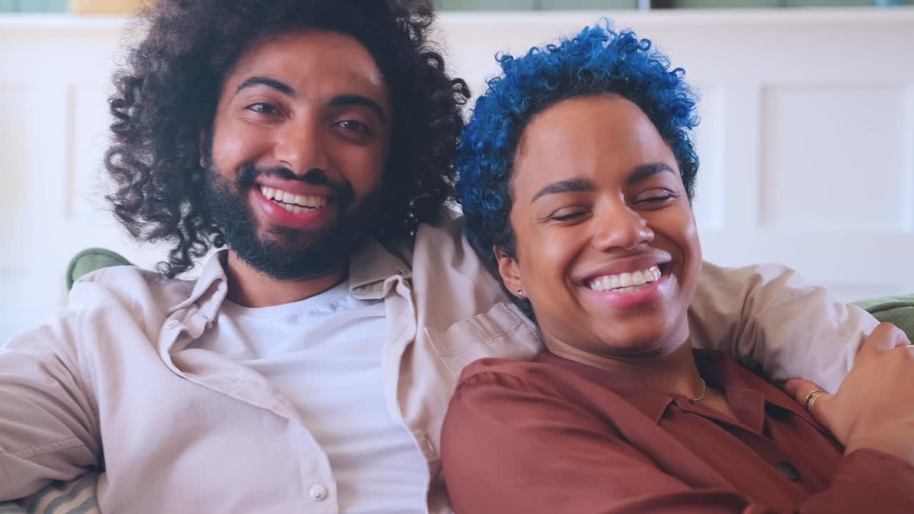 Young multiethnic cheerful couple free from racial prejudice sits on sofa