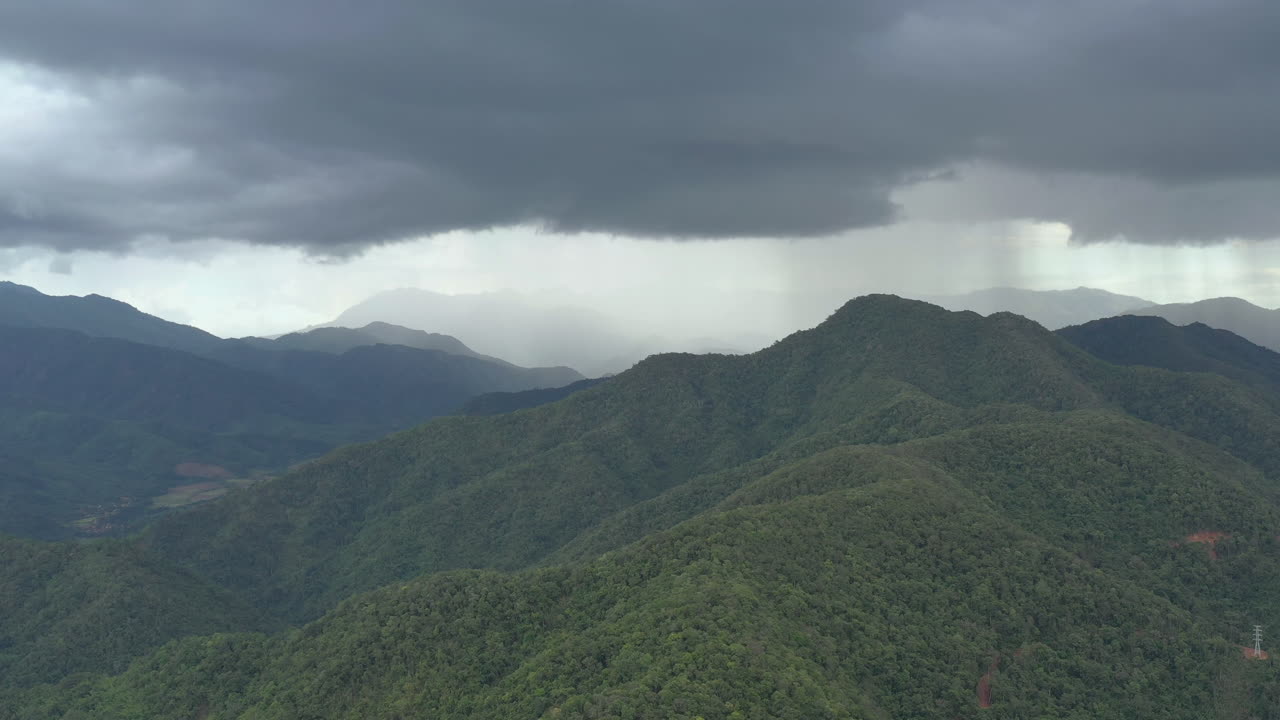 Flying through the stormy day above green mountain tops. 4K aerial view of the rainforest