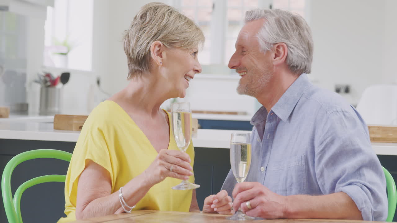 키스하는 은퇴 한 부부 는 데이트 밤 에 집 에서  ⁇ 페인 한 잔 을 마시며 함께 축하 하고 있다