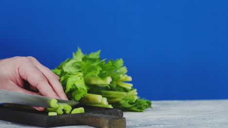male hand cut fresh celery into pieces.