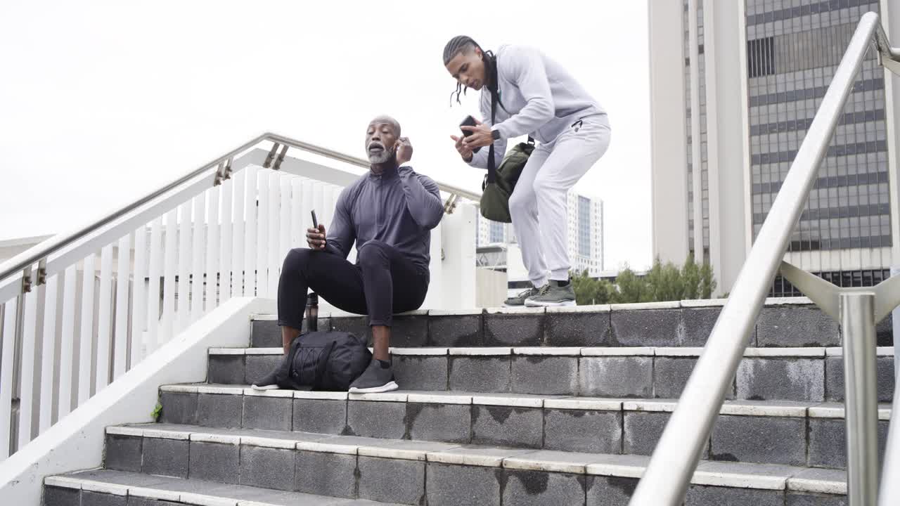 Diverse male strangers exchanging smartwatch tips on urban stairs after shoulder tapping