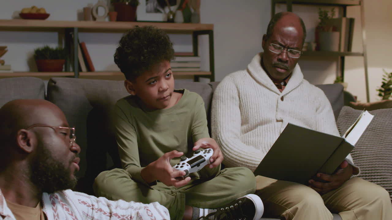 Black men and boy in the living room at night