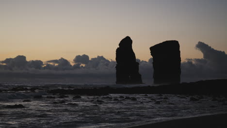 Silhouettes-of-cliffs-in-ocean-by-coast-of-the-Azores-at-dusk,-static