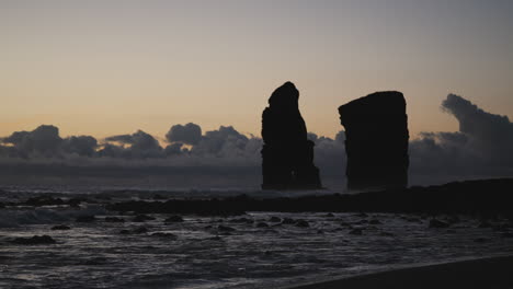 silhouettes of cliffs in ocean by coast of the azores at dusk, static