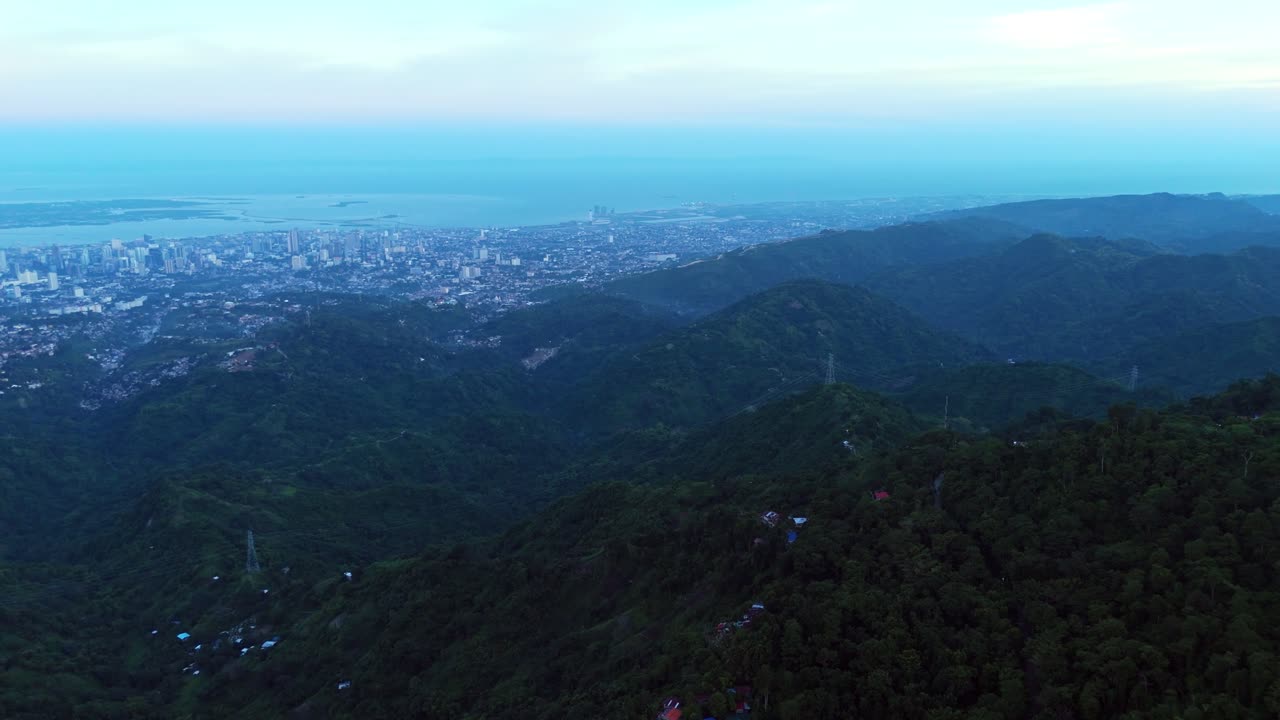 Wide drone aerial of Cebu City skyline, ocean horizon, and lush tropical mountains. Perfect for travel, tourism, cityscape, and establishing scene visuals