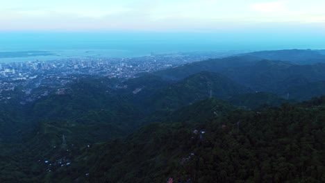 wide drone aerial of cebu city skyline, ocean horizon, and lush tropical mountains. perfect for travel, tourism, cityscape, and establishing scene visuals