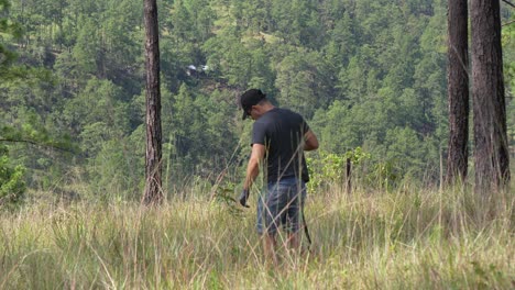 ecologist man planting a tree in the forest with a tool