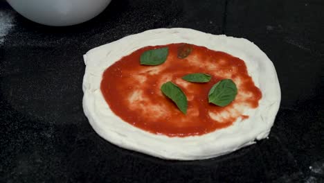 chef putting basil leaves on italian pizza in slow motion