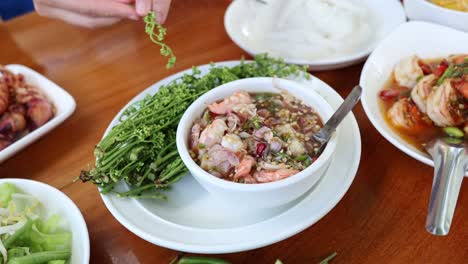 hands garnishing and mixing a bowl of food