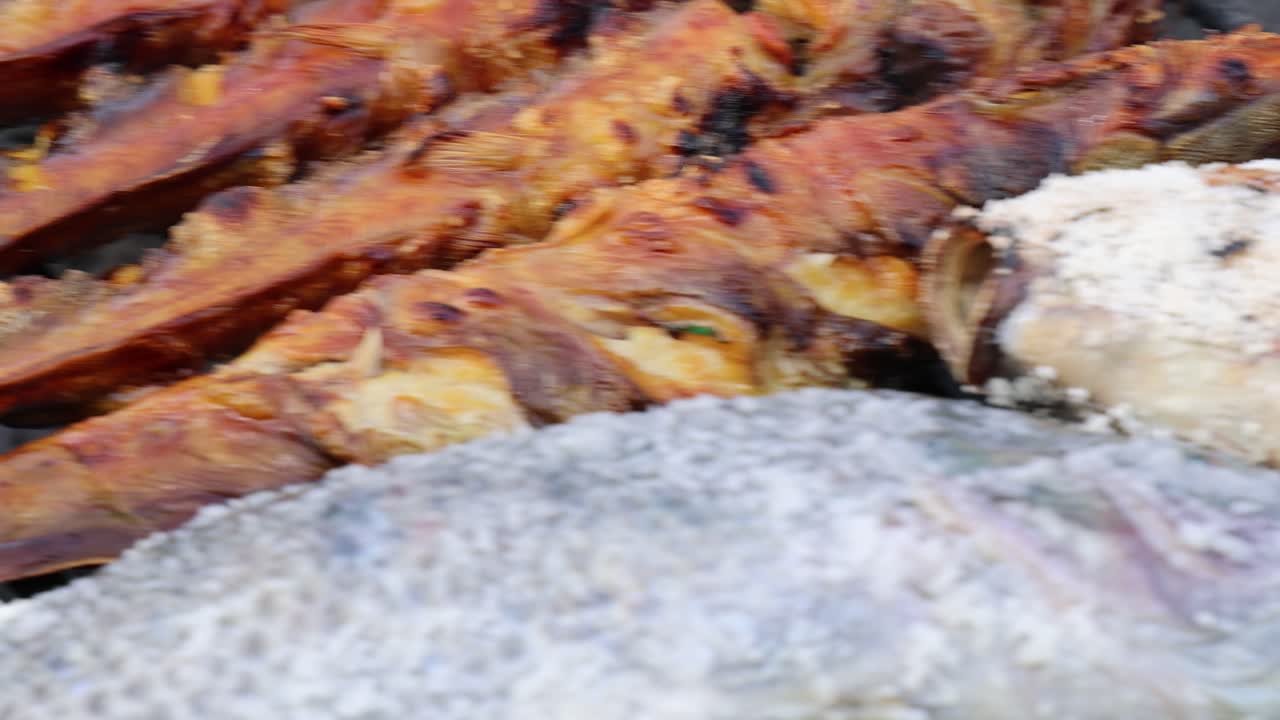Pesce in crosta di sale grigliato sulla brace, fumo che sale, primo piano, luce naturale, ambientazione da mercato all'aperto