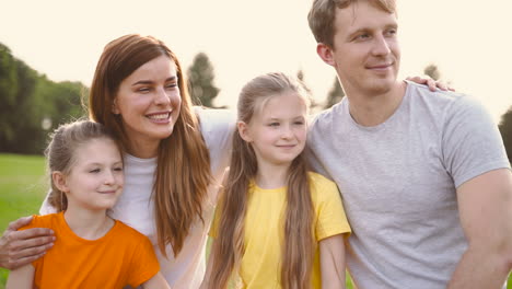 Retrato-De-Una-Familia-Feliz-Abrazando-Y-Mirando-Algo-Interesante-Mientras-Pasan-Tiempo-Juntos-En-El-Parque