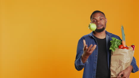 hombre confiado haciendo malabarismos con una manzana verde ecológica en la cámara