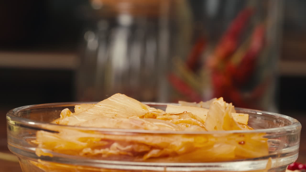 Primo piano di kimchi di cavolo piccante fermentato preso con le bacchette. Conservazione di verdure in barattoli di vetro. Macro di cavolo kimchi fermentato e conservato con spezie. Cucina asiatica.