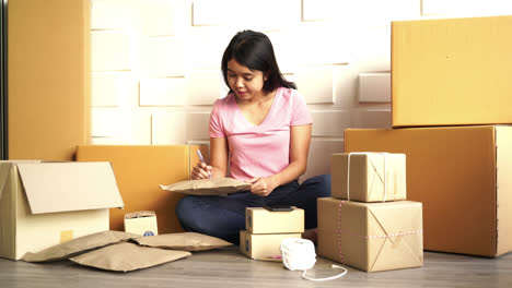 asian women business owner working at home with packing box on workplace