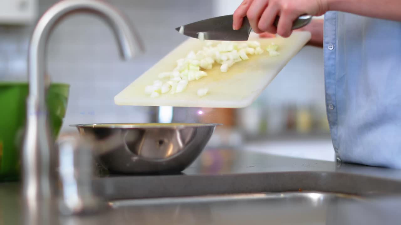 Animazione di luce sul busto di un uomo che cucina usando un coltello e un tagliere in cucina.