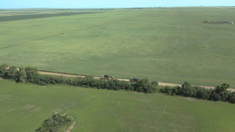 Road-graders-levelling-gravel-road,-Saskatchewan,-Canada,-drone-tilt-up-reveal-shot