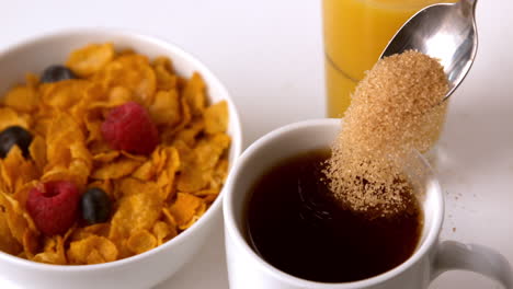 azúcar vertiendo en la taza en la mesa del desayuno
