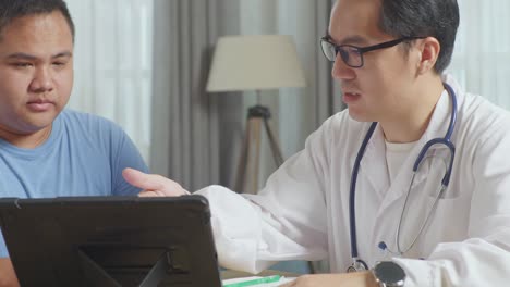 close up of asian male doctor with a fat male patient in clinic, sitting at desk and discussing about the results of medical check up on a tablet